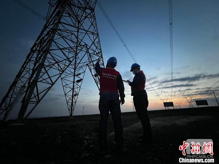 2023年1月16日，国网新疆信通公司运维人员在电力杆塔处勘察自供能传感器应用条件。　李庆　摄